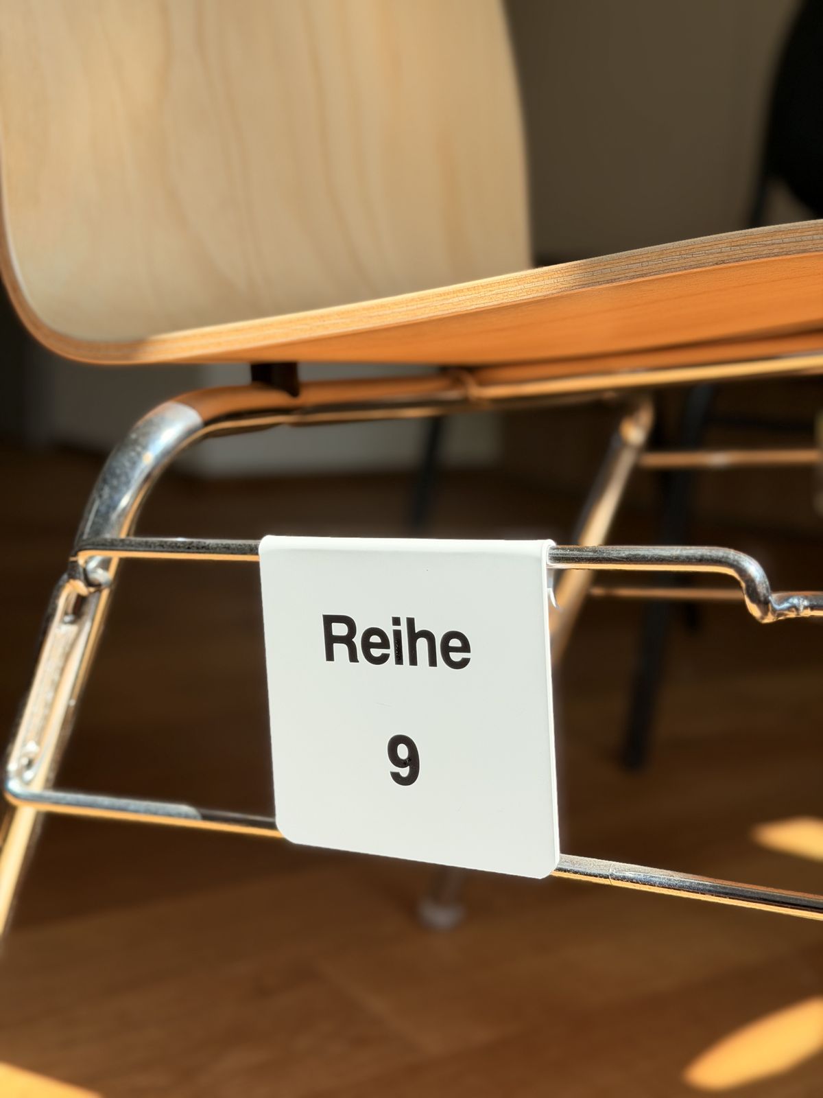 Weißes Reihenschild Reihe 9 montiert am Stuhlgestänge