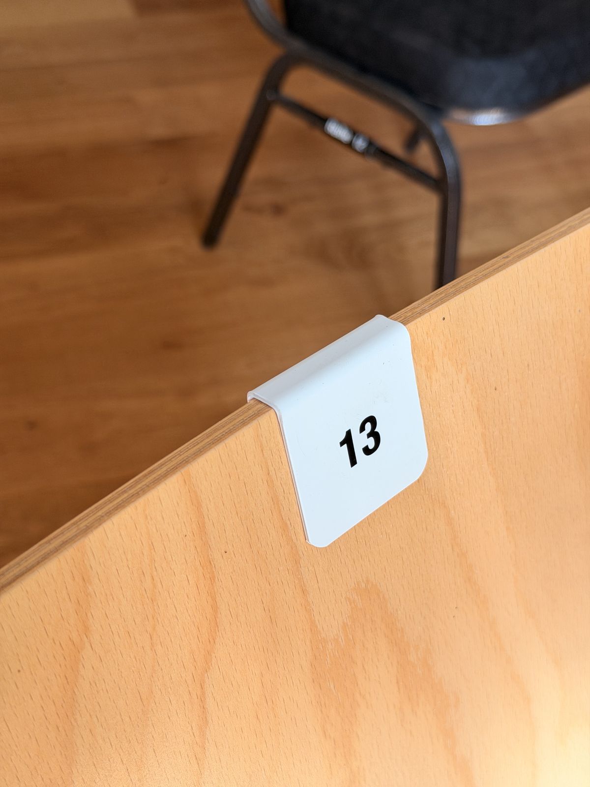 Weiße Stuhlnummer 13 zum Aufstecken auf einer Holzlehne